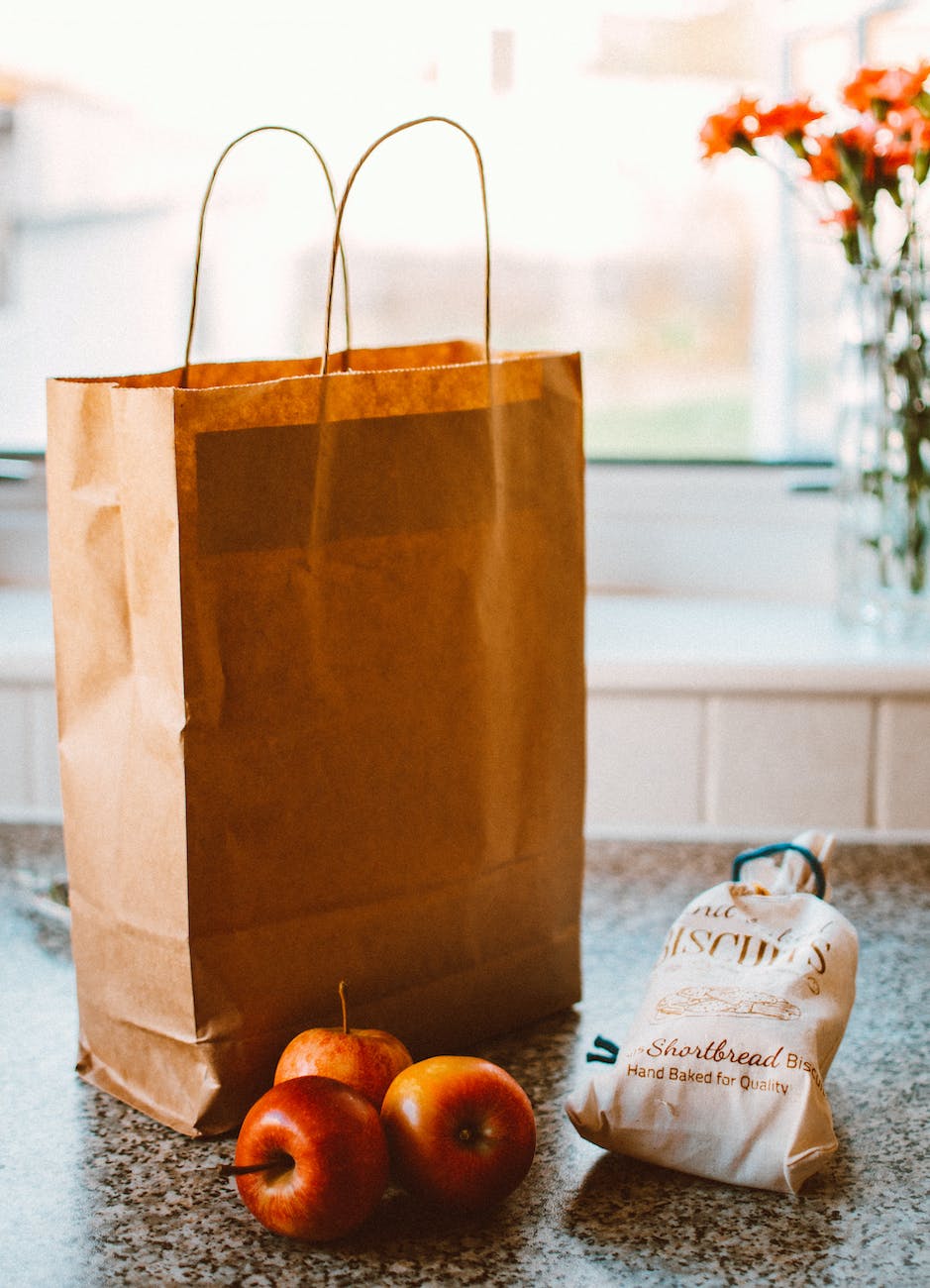 several apples beside bread pack and brown paper bag