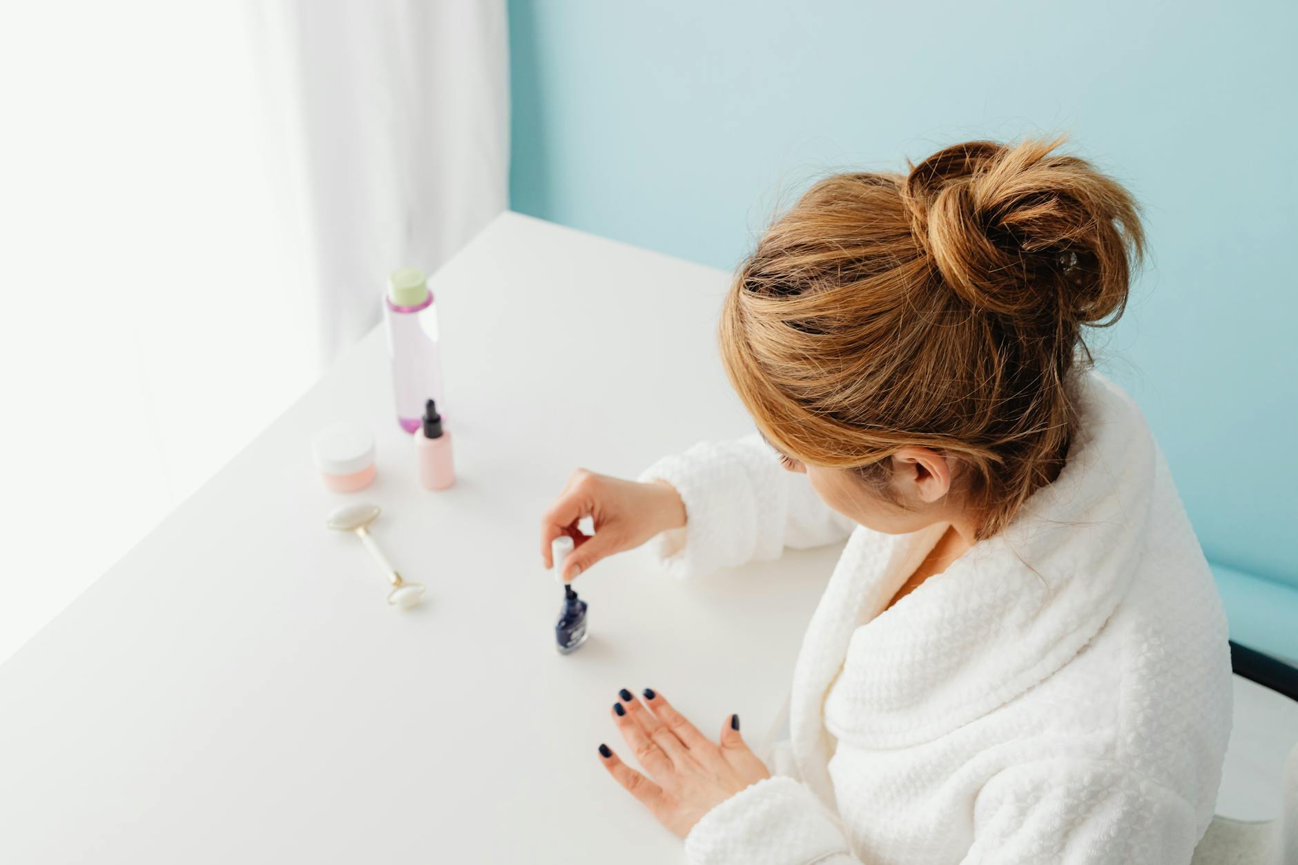 woman in bathrobe painting her nails