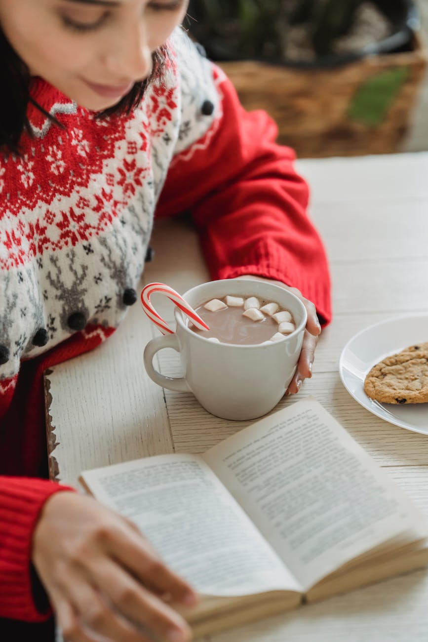 a woman holding hot chocolate reading a book