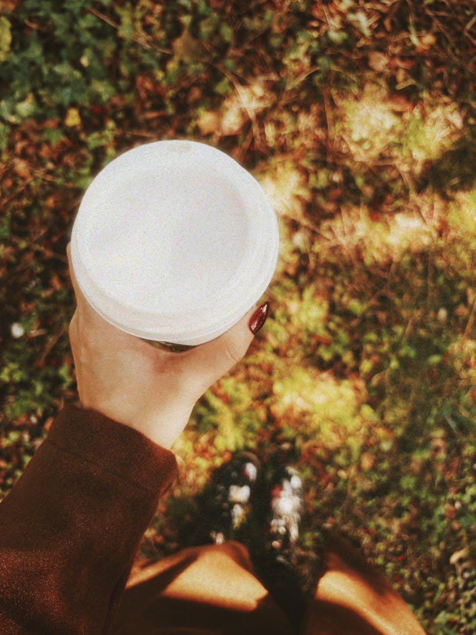 stylish woman holding coffee outdoors in fall